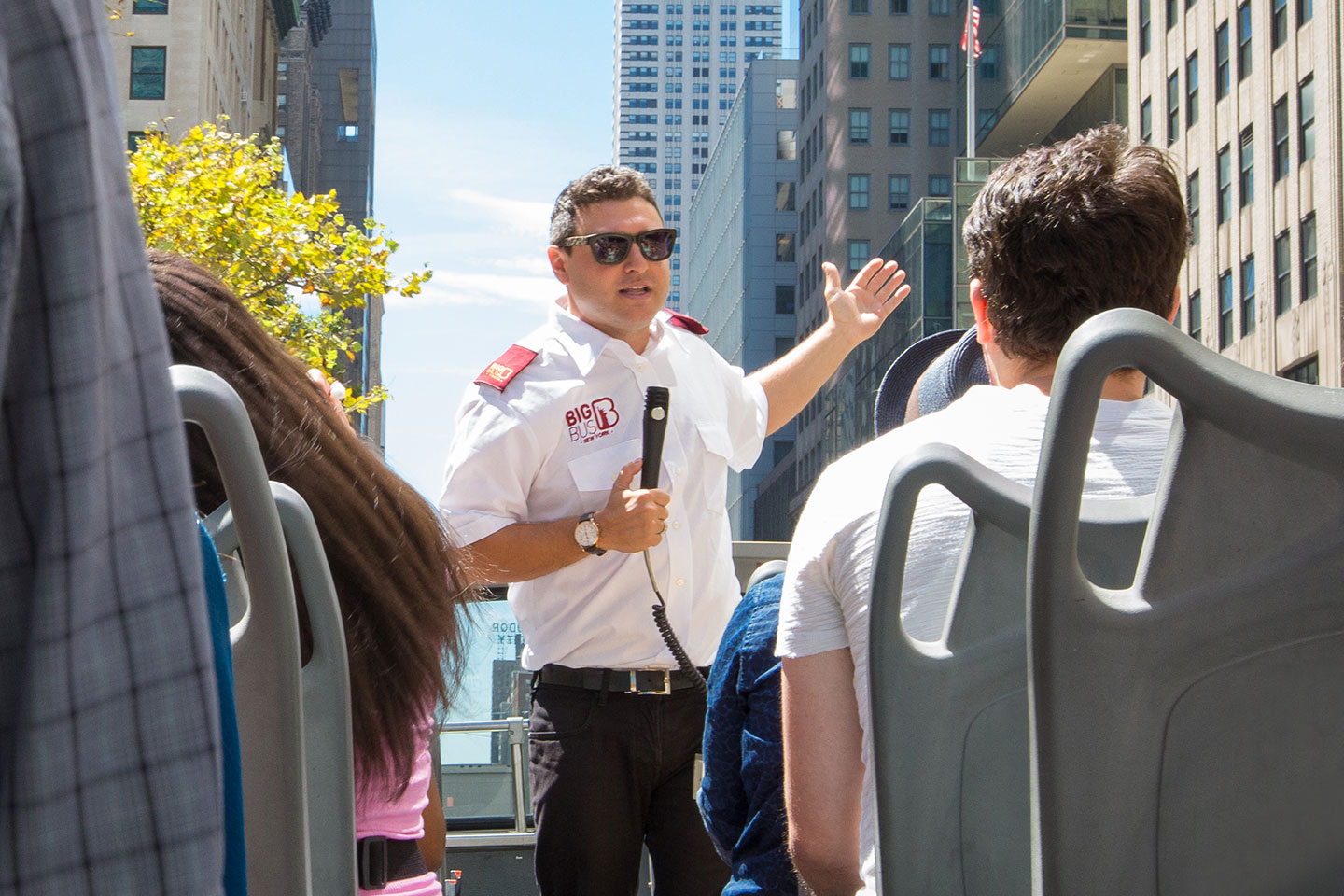 Big Bus tour guide with microphone on top of a bus