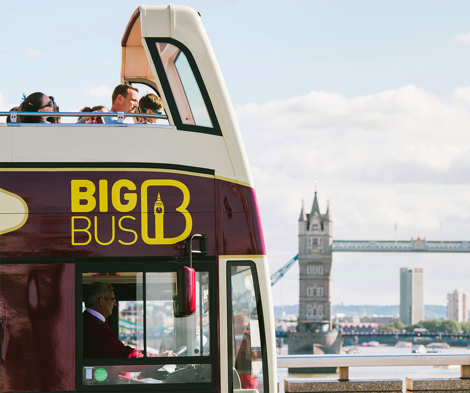Big Bus with passengers on the top deck looking at Tower Bridge